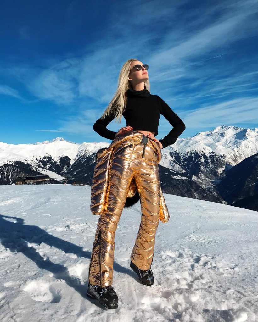 An influencer stands on a snow-covered mountain.